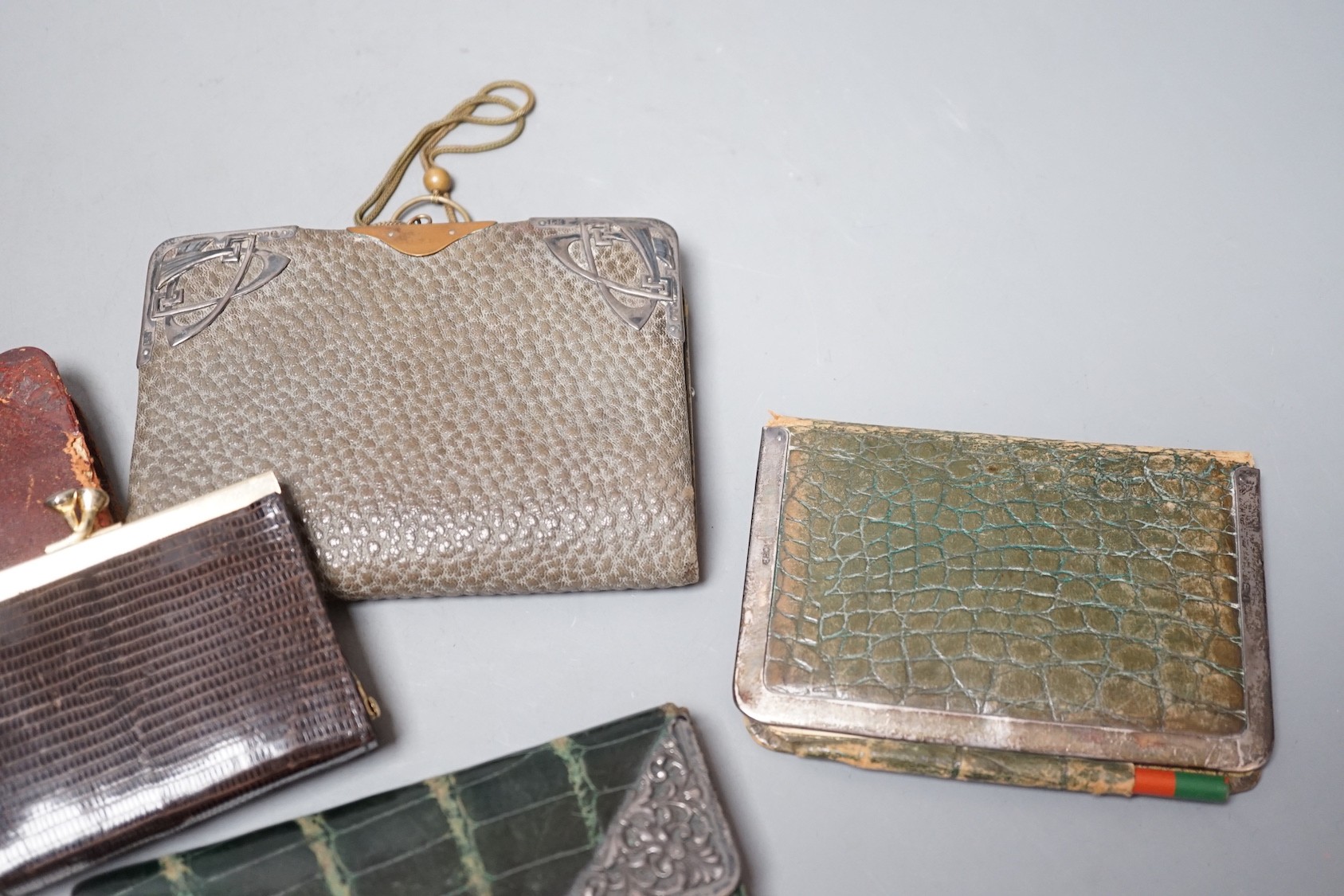 Five assorted early 20th century silver mounted leather purses including Art Nouveau, a similar notebook and one other purse.